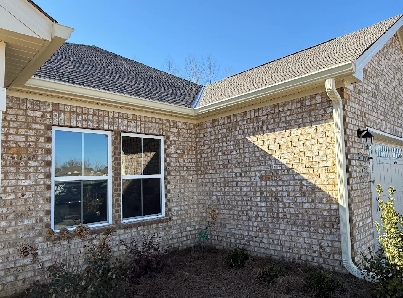 Light-colored gutters turning a corner above a brick home