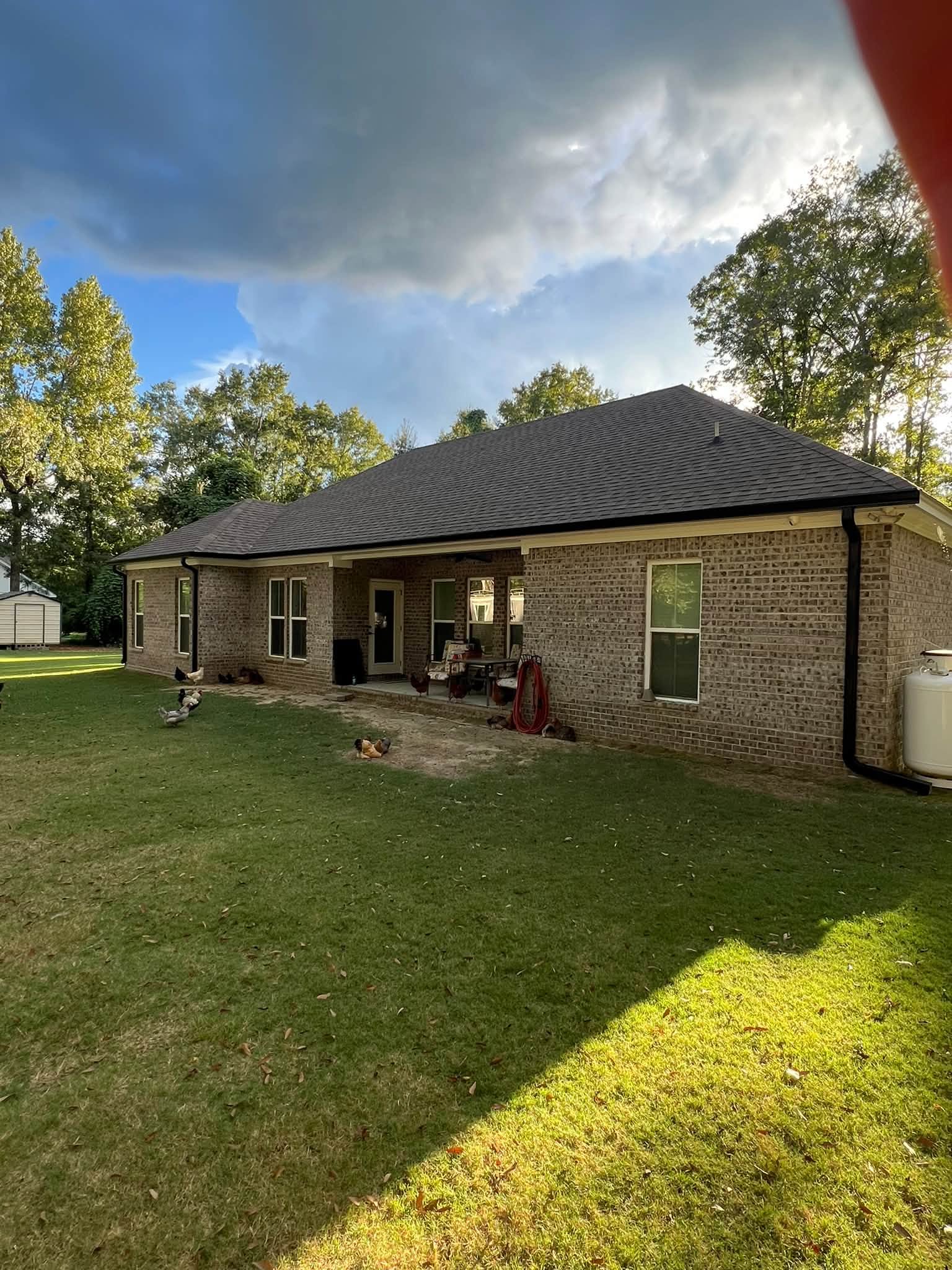 Black gutters and downspouts across the rear of a brick home