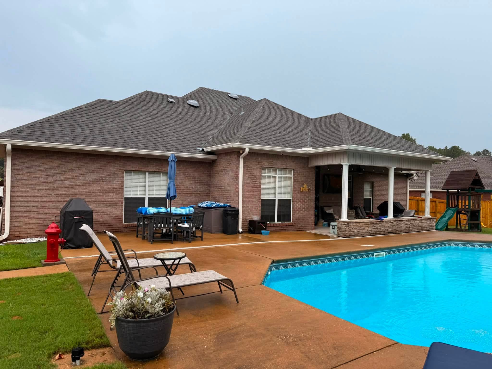 White gutters and downspouts at a poolside brick home